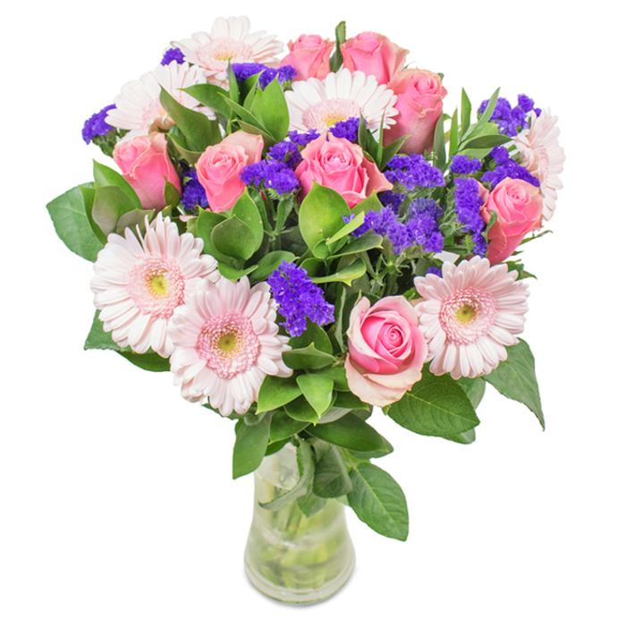 An elegantly composed bouquet, precisely presented in a clear glass vase and placed against a crisp white backdrop, showcases the skill and style rooted in Crystal Palace's vibrant community. Seven to nine classic pink roses take center stage, many with petals still tightly curled, echoing the timeless charm of the Victorian terraces nearby. Five to seven pale pink gerbera daisies, known for their generously sized, round blooms with slightly lighter centers, nestle alongside, bringing warmth and inviting texture. Scattered between these two stars, bright purple statice illuminates the arrangement with pops of colour and intriguing contrast, as lively as a Saturday in Haynes Lane Market. Deep green foliage forms a lush, refreshing base, suggesting the natural abundance of Crystal Palace Park. Each stem is visible within the polished clear glass vase, complete with water for a look of freshness that echoes the local florist's promise. Whether marking a birthday on Anerley Road, celebrating a family milestone, or elevating a front room along Westow Street, this bouquet is perfect for expressing joy, appreciation, and Crystal Palace flair in every petal.