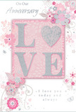 In this image, a softly romantic anniversary card lies as though just opened beside a bouquet of pastel flowers in a Crystal Palace home. The focal point is the word "LOVE," set in uppercase letters that rise slightly from the card's surface, each form edged with a fine dusting of glitter. The glitter has a muted, silvery quality, giving the letters a refined sparkle similar to moonlight glancing across the glass roof of Crystal Palace station on a clear night. The word rests on a gentle blush-pink panel, centered against a background washed in pale pinks, pearly whites, and hints of soft grey. Framing this central motif is an array of illustrated blossoms, curling vines, and slender leaves, which sweep around the word in delicate arcs. The blooms unfold in shades of blush, mauve, and ivory, their outline drawn with precise yet fluid strokes that resemble a florist's notes for a spring-inspired anniversary bouquet. Silver accents trace some of the petal edges and stems, creating subtle highlights that catch the eye without overpowering the softness of the design. Finely drawn flourishes-tiny petals, swirling tendrils, and faint butterflies-add a sense of light movement, like petals stirred by a breeze along Westow Street. Above and below, graceful script phrases such as "On Our Anniversary" and "I love you today and always" are carefully placed, their shapes echoing the lines of the surrounding vines. The card's overall mood is intimate and tender, like a whispered promise shared over dinner at home after flowers and this card have been delivered from a nearby Crystal Palace florist, celebrating love that has deepened over time.